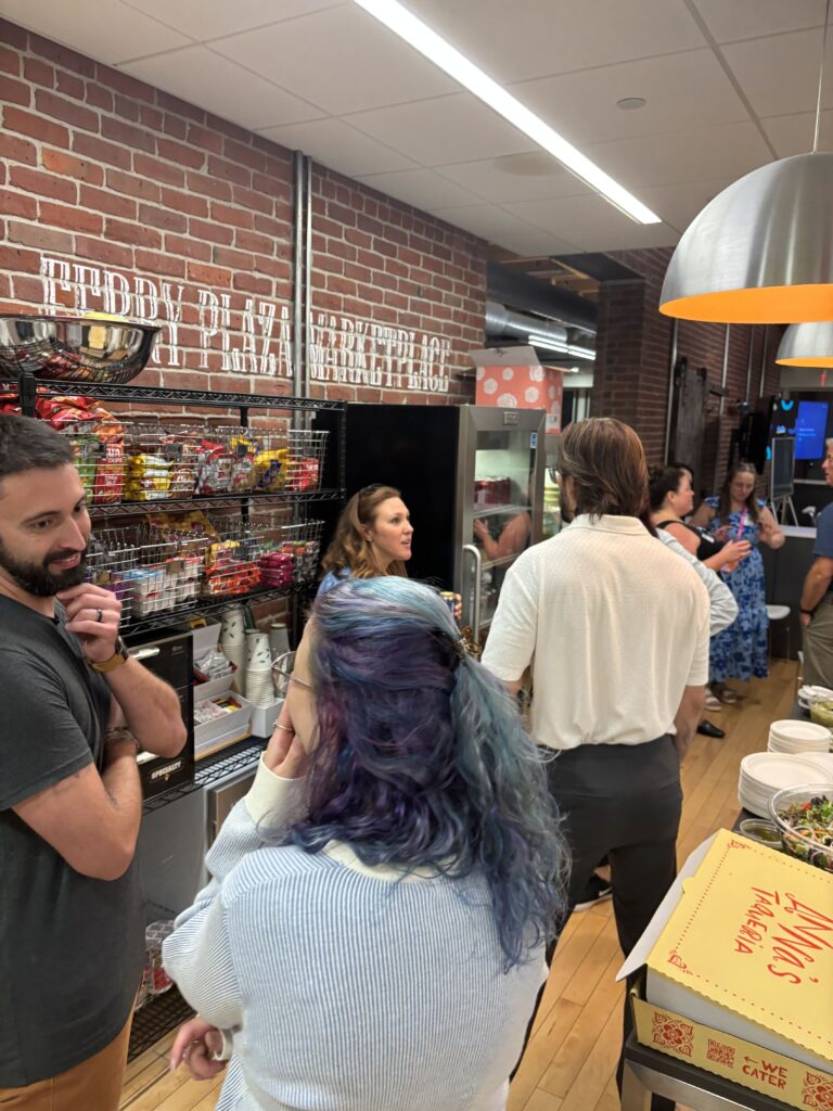 Guests chatting in the office kitchen beside a brick wall